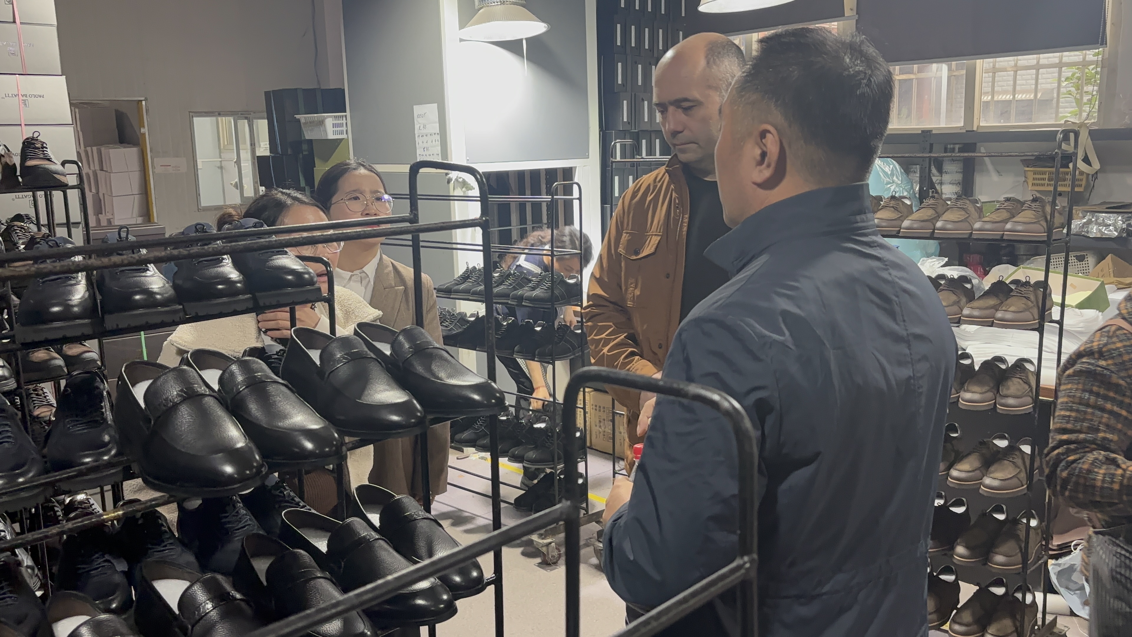 International buyer discussing custom leather loafer samples with factory representatives on a showroom visit, highlighting professional OEM communication and quality assurance for global clients.