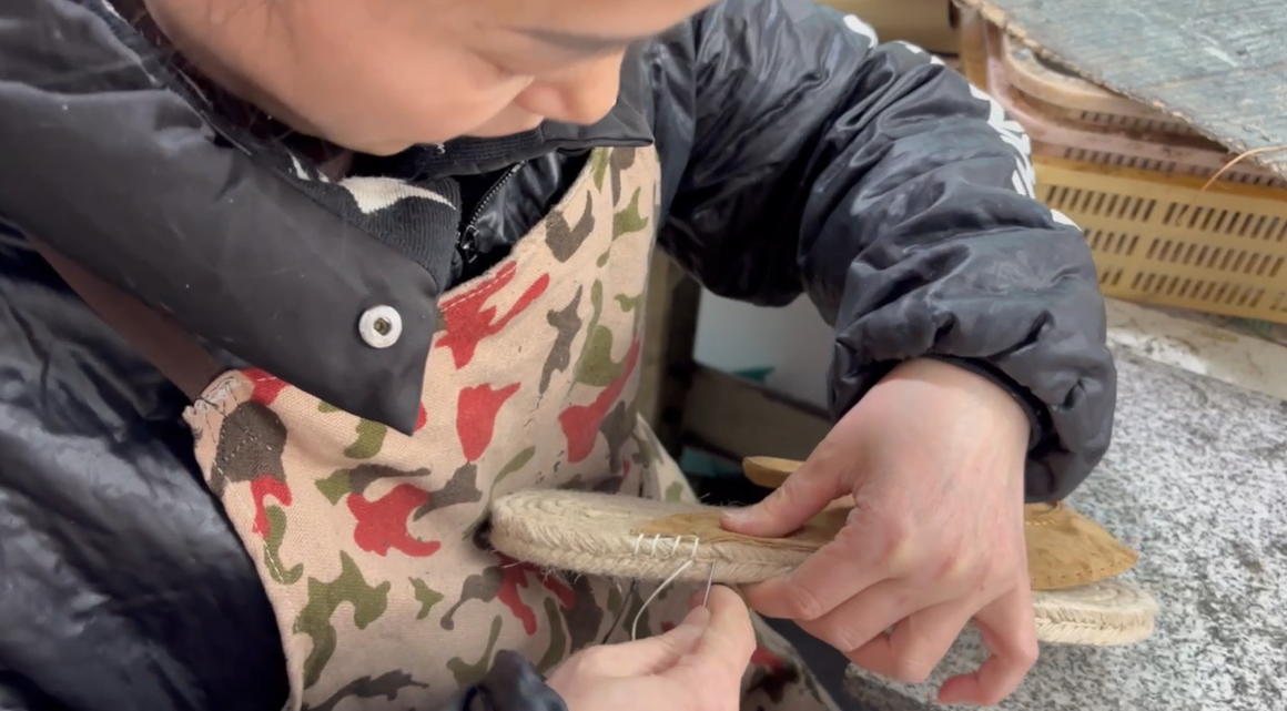 Skilled artisan hand-stitching shoe soles with needle and thread at LANCI footwear manufacturer